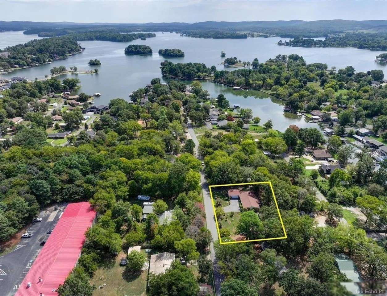 Aerial view of 186 Echo Point, a single-level home among the trees with Lake Hamilton beyond